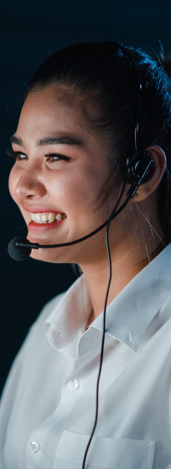 Millennial Asia young call center team or customer support service executive using computer and microphone headset working technical support in late night office. Telemarketing or sales job concept.